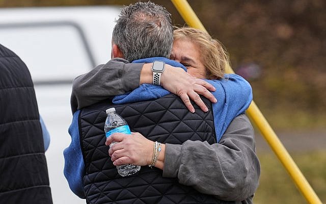 People embrace as law enforcement escort families away from the Temple Israel synagogue Thursday, March 12, 2026, in West Bloomfield Township, Mich. (AP Photo/Paul Sancya)