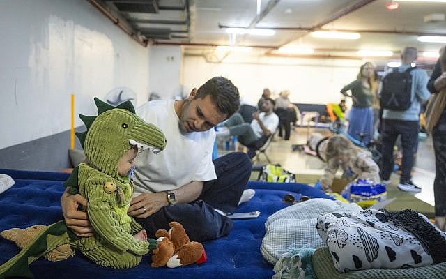 People take cover at an undergoing parking lot from incoming missiles fired from Iran, in Tel Aviv, March 3, 2026. (Chaim Goldberg/Flash90)