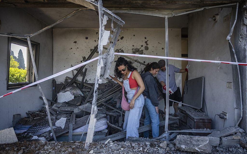 People at the scene where a house was hit by a missile fired toward Israel overnight in Moshav Hani’el, March 12, 2026. (Chaim Goldberg/Flash90)