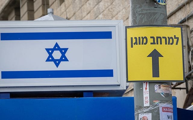 An Israeli flag is seen next to a sign pointing toward a protected space outside the Mahane Yehuda Market in Jerusalem amid the ongoing war with Iran and Hezbollah and missile fire toward Israel, March 26, 2026. Photo by Chaim Goldberg/Flash90 An Israeli flag is seen next to a sign pointing toward a protected space outside the Mahane Yehuda Market in Jerusalem amid the ongoing war with Iran and Hezbollah and missile fire toward Israel, March 26, 2026. Photo by Chaim Goldberg/Flash90
