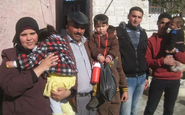 Standing outside their Hebron home before leaving for Holon to receive treatment from Save a Child's Heart, (from left), Lubna Abu Danash holding her daughter Shuruk, Mahmoud Abu Danash holding Muath, and his older brothers. (photo credit: Ilan Ben Zion/Times of Israel staff)