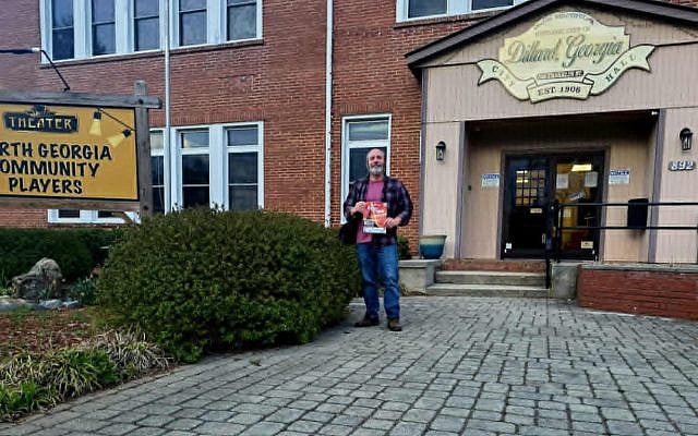 Atha Thomas, who plays Tevye in the North Georgia Community Players production of Fiddler on the Roof, stands outside the theatre holding the production flyer. (Carly McCurry)