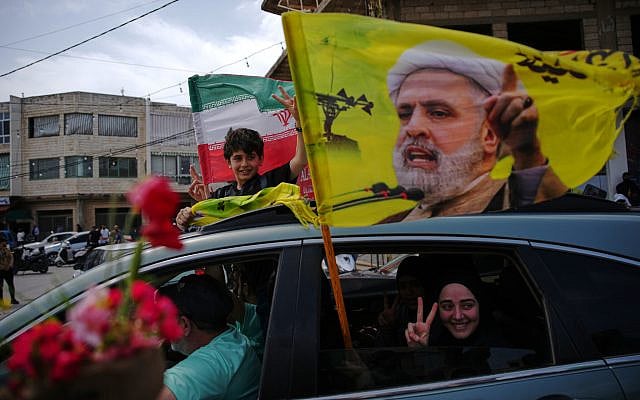 Displaced residents wave a flag with the image of Hezbollah leader Naim Qassem as they return to their villages following a ceasefire between Israel and Hezbollah, in Zefta, southern Lebanon, Friday, April 17, 2026. (AP Photo/Hassan Ammar)