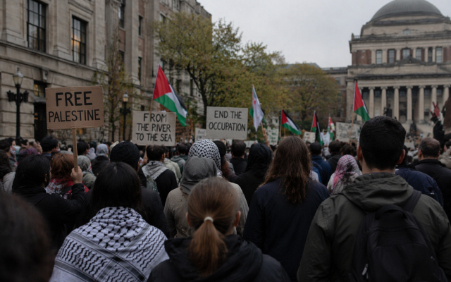 Students gather on a university campus during a pro-Palestinian protest, holding signs reading 'Free Palestine,' 'From the river to the sea,' and 'End the occupation,' with Palestinian flags visible. (AI-generated illustration)