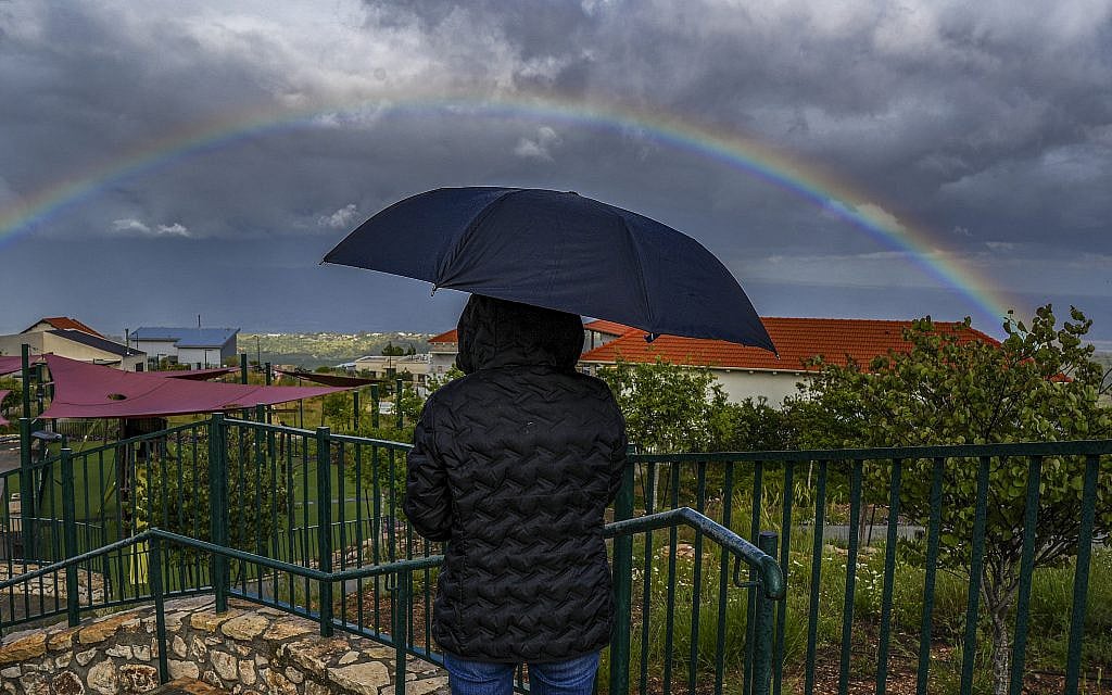 A person stands under an umbrella as a rainbow appears in the sky in the Upper Galilee, northern Israel, May 4, 2026. Photo by Ayal Margolin/Flash90