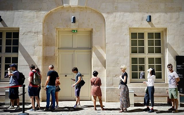 A group of people standing outside in a line. (Photo by Meizhi Lang/Unsplash).