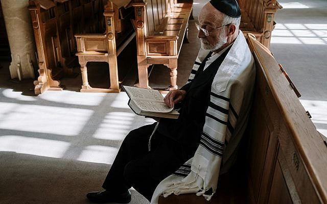 Elderly man wearing kippah and tallit, reading in a synagogue. Traditional Jewish setting. As taken from the website Pexels (https://www.pexels.com/photo/an-elderly-man-reading-a-book-5974271/).