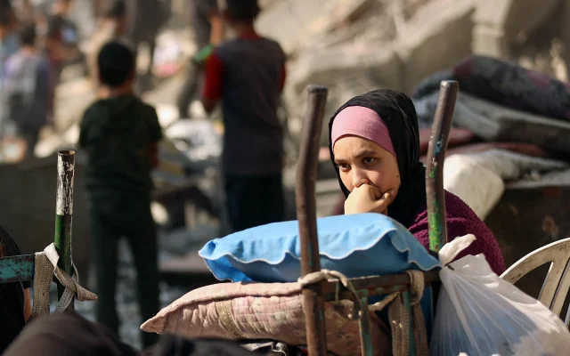 A woman watches as Palestinians retrieve items from the rubble of a destroyed building following overnight Israeli army bombardment on al-Shati camp for Palestinian refugees, west of Gaza City, on September 12, 2025. (Photo by Omar AL-QATTAA / AFP)