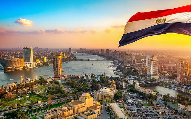 The Nile River winding through the Cairo skyline at sunset, beneath the Egyptian flag. (Illustrative photo: Canva)