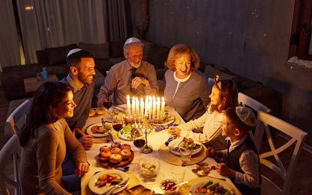 Happy extended family communicating while having a late meal on Hanukkah in dining room.