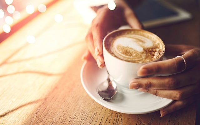A woman's hands, holding a cup of coffee. (iStock)