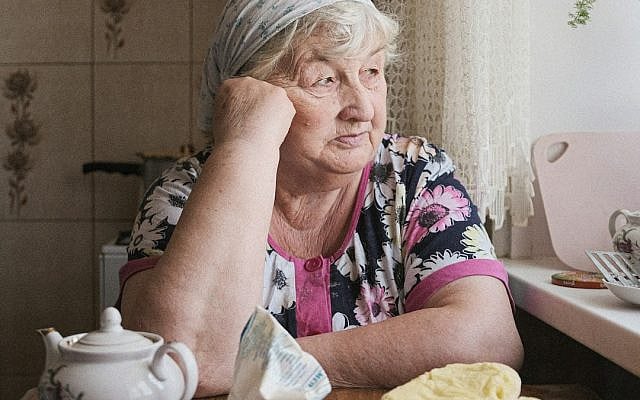 A woman sitting at a table with food on it. (Photo by Anton Luk/Unsplash)