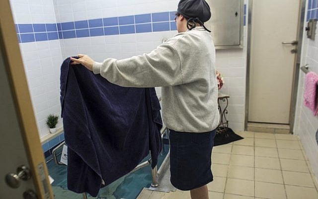A mikveh attendant supervises a woman immersing. (Heidi Levine, via The Eden Center)