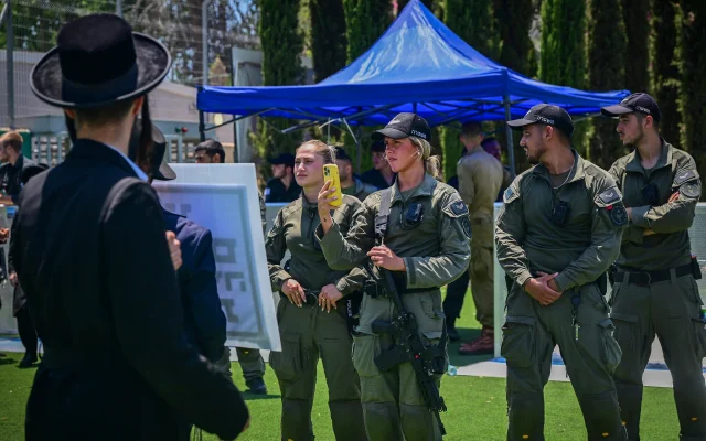 Troops watch as ultra-Orthodox men protest against the draft outside the IDF Recruitment Center at Tel Hashomer, July 15, 2026. (Avshalom Sassoni/Flash90)