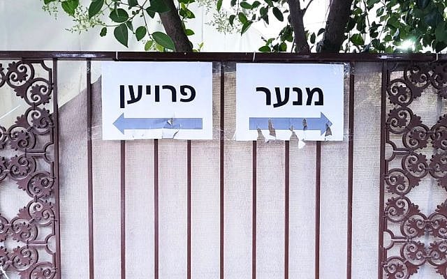 Gender-segregation signage on Hizkiyahu HaMelech Street in Katamon, Jerusalem, during a Hachnasat Sefer Torah ceremony (2018).  The Yiddish signs direct men and women to separate walking routes. (Sarah Segal-Katz)