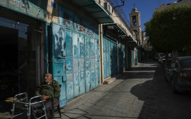 A man rests by a row of empty shops near the Church of the Nativity, where Christians believe Jesus Christ was born, ahead of Christmas in the West Bank city of Bethlehem, December 17, 2024. (Mahmoud Illean/AP)