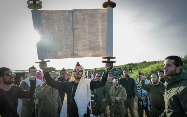 IDF Reserve soldiers and Orthodox Jews take part in prayer and the weekly reading of a Torah Scroll at dawn just before a military exercise on the Golan Heights, April 1, 2024. (Michael Giladi/ Flash90)