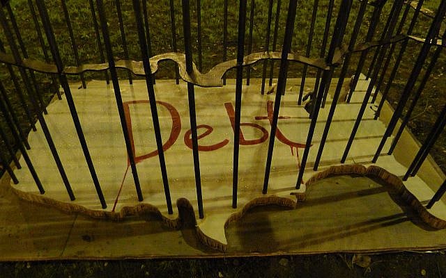Sculpture depicting the continental United States of America bordered by metal bars referencing a jail cell, with the word "Debt" painted in red on the outline of the USA.
via ArtofCulturalEvolution, "Debt", art installation during Occupy Portland, CC BY-SA 3.0 Sculpture depicting the continental United States of America bordered by metal bars referencing a jail cell, with the word "Debt" painted in red on the outline of the USA.
via ArtofCulturalEvolution, "Debt", art installation during Occupy Portland, CC BY-SA 3.0