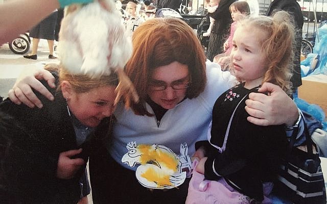 Henny Kupferstein, wearing a sheitel over her shaved head, holds her children during kapparot, as a chicken is waved over their heads in the symbolic atonement ritual practiced by many Chassidim before Yom Kippur.