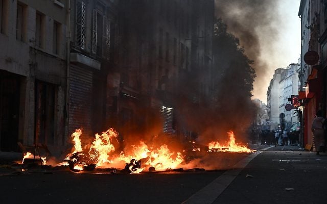 Trash burns during clashes between protestors and police officers during a demonstration against rising living costs, joining students' grievances, in Paris, Sunday, Oct. 18, 2026. (AP Photo/Emma Da Silva)