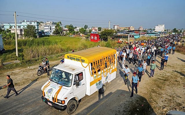 Mourners and security personnel walk behind a truck carrying the coffin of Bipin Joshi, the slain Nepali hostage, during a funeral ceremony at his hometown in Kanchanpur on October 21, 2025. (Prakash Chandra Timilsena / AFP)