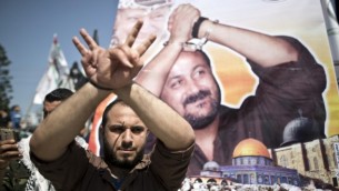 توضیح تصویر: مردی فلسطینی در مقابل پوستر رهبر زندانی فتح، مروان برقوتی، در تظاهرات روز زندانیان فلسطینی در شهر غزه، ۱۷ آوریل ۲۰۱۶، دستها را با ژست بالا برده توضیح تصویر: مردی فلسطینی در مقابل پوستر رهبر زندانی فتح، مروان برقوتی، در تظاهرات روز زندانیان فلسطینی در شهر غزه، ۱۷ آوریل ۲۰۱۶، دستها را با ژست بالا برده