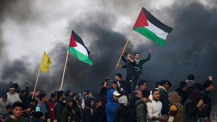 توضیح تصویر: تزئینی، معترضین فلسطینی با پرچم ملی حین زدوخورد با مأموران امنیتی اسرائیلی در حومه‌ی شرقی شهر غزه، نزدیک مرز اسرائیل، ۱۲ ژانویه ۲۰۱۸. (AFP Photo/Mohammed Abed)