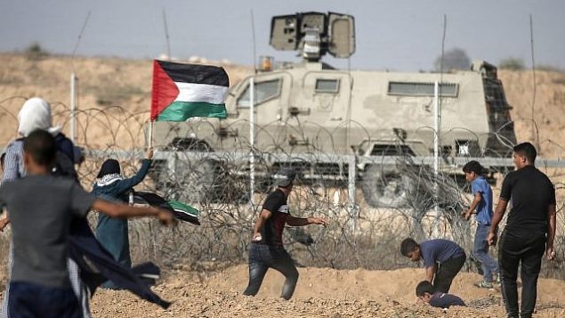 تصویر: تظاهرکنندگان فلسطینی حین تظاهرات در امتداد مرز با اسرائیل، شرق «خان یونس»، ناحیه جنوبی نوار غزه، به نیروهای امنیتی اسرائیل سنگ پرتاب میکنند، ۱۲ ژوئیه ۲۰۱۹. (MAHMUD HAMS / AFP)