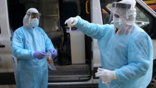 Palestinian health workers handling a Coronavirus test sample of Palestinian workers as they cross back from Israel at a checkpoint in Tarqumiya on March 25, 2020. Photo by Wisam Hashlamoun/Flash90  *** Local Caption *** קורונהוירוסחברון
							<p class=