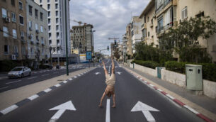 An Israeli man stands on his hands on an empty road during a lockdown following government measures to help stop the spread of the coronavirus, in Tel Aviv, Israel, Wednesday, April 8, 2020. Israeli Prime Minister Benjamin Netanyahu announced Monday a complete lockdown over the upcoming Passover holiday to control the country's virus outbreak, but offered citizens some hope by saying he expects to lift widespread restrictions after the week-long Jewish holiday of Passover. (AP Photo/Oded Balilty)