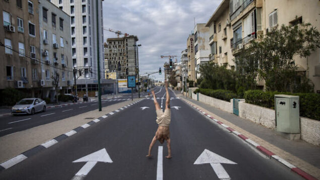 An Israeli man stands on his hands on an empty road during a lockdown following government measures to help stop the spread of the coronavirus, in Tel Aviv, Israel, Wednesday, April 8, 2020. Israeli Prime Minister Benjamin Netanyahu announced Monday a complete lockdown over the upcoming Passover holiday to control the country's virus outbreak, but offered citizens some hope by saying he expects to lift widespread restrictions after the week-long Jewish holiday of Passover. (AP Photo/Oded Balilty)