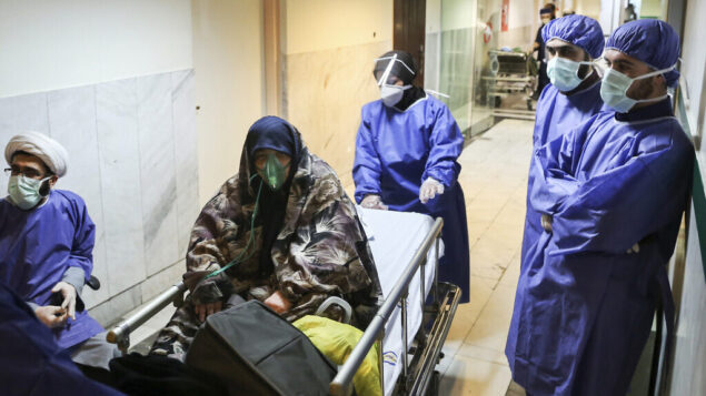 FILE - In this March 7, 2020 file photo, a patient infected with the new coronavirus is moved, at Baqiyatallah Al'Azam Hospital that is affiliated to the Revolutionary Guard, in Tehran, Iran. While crippling sanctions imposed by the U.S. government left the country ill-equipped to deal with the fast-moving virus, some medical professionals say government and religious leaders bear the brunt of the blame for allowing the virus to spread -- and for hiding how much it had spread. (Mohammad Hasan Zarifmanesh/Tasnim News Agency via AP, File)