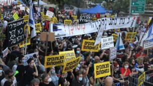 Israelis wearing masks to avoid the spread of the Covid-19 coronavirus protest against Israeli Prime Minister Benjamin Netanyahu outside his official residence in Jerusalem, on July 14, 2020. - Netanyahu, 70, was indicted in January for bribery, fraud and breach of trust in three cases. He denies all the charges and accuses the media and legal officials of a witch hunt. (Photo by Menahem KAHANA / AFP)