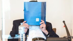 Bruno Dey, a former SS-watchman at the Stutthof concentration camp, hides his face behind a folder at the start of a hearing in his trial on July 23, 2020 in Hamburg, northern Germany. - The 93-year-old former Nazi concentration camp guard was handed a suspended sentence of two years in prison as a court in Hamburg found him guilty of complicity in WWII atrocities. In what could be one of the last such cases of surviving Nazi guards, Bruno Dey was convicted for his role in the killing of 5,230 people when he was a teenaged SS tower guard at the Stutthof camp near what was then Danzig, now Gdansk, in Poland. (Photo by Daniel Bockwoldt / POOL / AFP)