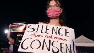 An Israeli woman wearing a protective mask due to the COVID-19 pandemic, holds a placard as she takes part in a demonstration in Tel Aviv on August 23, 2020, to denounce sexual violence against women following the alleged gang-rape of a 16-year-old girl in a Red Sea resort. - Police said 11 suspects, including nine minors and a woman said to be the manager of the hotel in which the alleged rape took place, had been arrested in connection with the affair so far as part of an "ongoing investigation". (Photo by JACK GUEZ / AFP)