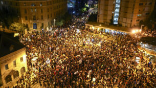 Thousands of protesters chant slogans and hold signs during a protest against Israel's Prime Minister Benjamin Netanyahu outside his residence in Jerusalem, Saturday, Aug 1, 2020. Protesters demanded that the embattled Israeli leader to resign as he faces a trial on corruption charges and grapples with a deepening coronavirus crisis. (AP Photo/Oded Balilty)