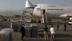 Aid supplies are collected on the tarmac prior to being loaded on to a plane bound for Beirut, Lebanon, part of a humanitarian assistance effort after a massive explosion on Tuesday, as a plane takes off from Mehrabad Airport in Tehran, Iran, Wednesday, Aug. 5, 2020. Residents of Beirut awoke to a scene of utter devastation on Wednesday, a day after a massive explosion at the port sent shock waves across the Lebanese capital, killing dozens of people and wounding thousands. (AP Photo/Vahid Salemi)