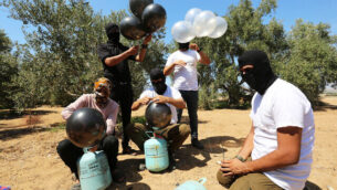 Palestinian men prepare a flammable object to be flown toward Israel, near the Israel-Gaza border, in the eastern part of the Gaza Strip, August 10, 2020. Photo by Abed Rahim Khatib/Flash90 *** Local Caption *** פלסטיניםרצועת עזהגבול
							<p class=