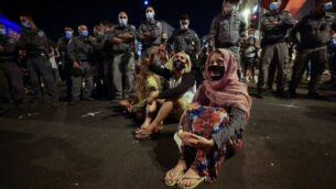 Israeli protesters sit amongst policemen during a demonstration amid a second lockdown in front of Prime Minister Benjamin Netanyahu's residence in Jerusalem, on September 26, 2020, to protest the government's handling of the COVID-19 pandemic. - Thousands of Israelis gathered in Jerusalem to demand the resignation of Prime Minister Benjamin Netanyahu, a day after the country tightened its lockdown aimed at slowing coronavirus spread. (Photo by Emmanuel DUNAND / AFP)