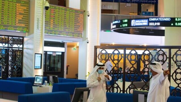 Two Emiratis wearing face masks due to the coronavirus pandemic talk on the floor of the Dubai Financial Market in Dubai, United Arab Emirates, Tuesday, July 7, 2020. Dubai reopened its Dubai Financial Market stock exchange Tuesday after closing its floor due to the coronavirus pandemic. (AP Photo/Jon Gambrell) Two Emiratis wearing face masks due to the coronavirus pandemic talk on the floor of the Dubai Financial Market in Dubai, United Arab Emirates, Tuesday, July 7, 2020. Dubai reopened its Dubai Financial Market stock exchange Tuesday after closing its floor due to the coronavirus pandemic. (AP Photo/Jon Gambrell)