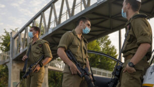 Israeli soldiers wear face masks during the three-week nationwide lockdown due to the coronavirus pandemic in a police roadblock in Tel Aviv, Israel, Saturday, Sept. 19, 2020. Israel went back into a full lockdown on Friday to try to contain a coronavirus outbreak that has steadily worsened for months as its government has been plagued by indecision and infighting. (AP Photo/Ariel Schalit)