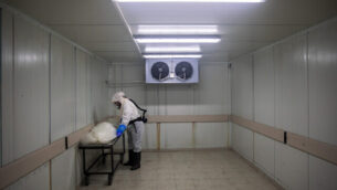 A worker from "Hevra Kadisha," Israel's official Jewish burial society, prepares a body before a funeral procession at a special morgue for COVID-19 victims in the central Israeli city of Holon, near Tel Aviv, Wednesday, Sept. 23, 2020. With Israel facing one of the world's worst outbreaks, burial workers have been forced to wear protective gear and take other safety measures as they cope with a growing number of coronavirus-related deaths. (AP Photo/Oded Balilty)