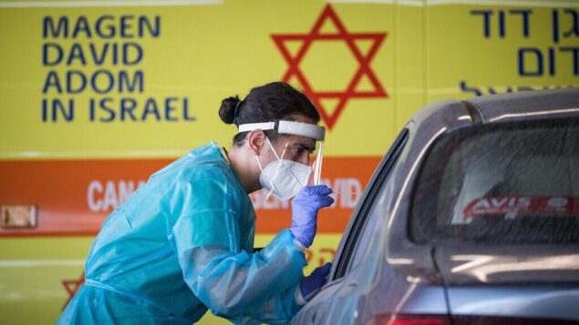 Shaare Zedek Medical team member wearing protective gear takes a swab from a woman to test for the coronavirus disease (COVID-19), outside the coronavirus unit at Shaare Zedek hospital in Jerusalem on September 24, 2020. Photo by Yonatan Sindel/Flash90 *** Local Caption ***