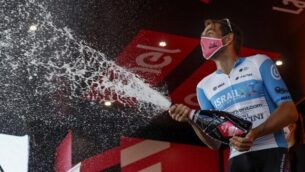 Team Israel Start-Up Nation rider England's Alex Dowsett wearing a face mask, celebrates with a bottle of champagne on the podium after winning the 8th stage of the Giro d'Italia 2020 cycling race, a 200-kilometer route between Giovinazzo and Vieste on October 10, 2020. (Photo by Luca Bettini / AFP)