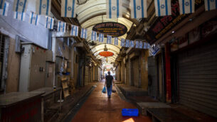 A man walks through a closed market on the first day of the three-week nationwide lockdown, in Tel Aviv, Israel, Friday, Sept 18, 2020. Israel went back into a full lockdown on Friday to try to contain a coronavirus outbreak that has steadily worsened for months as its government has been plagued by indecision and infighting. (AP Photo/Oded Balilty)
