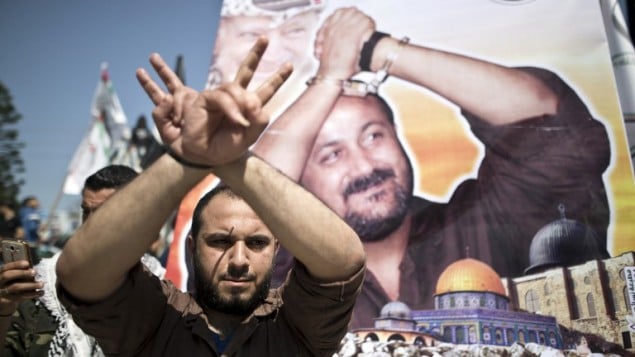توضیح تصویر: مردی فلسطینی در مقابل پوستر رهبر زندانی فتح، مروان برقوتی، در تظاهرات روز زندانیان فلسطینی در شهر غزه، ۱۷ آوریل ۲۰۱۶، دستها را با ژست بالا برده توضیح تصویر: مردی فلسطینی در مقابل پوستر رهبر زندانی فتح، مروان برقوتی، در تظاهرات روز زندانیان فلسطینی در شهر غزه، ۱۷ آوریل ۲۰۱۶، دستها را با ژست بالا برده