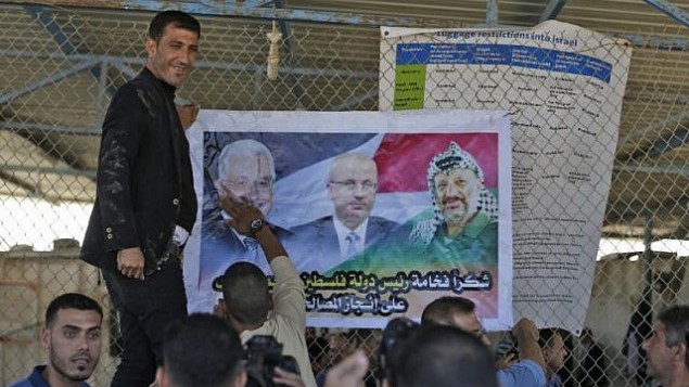مردان فلسطینی پوستری از محمود عباس رهبر فلسطینی (چپ)، رامی حمدالله نخست وزیر، و یاسر عرفات رهبر فقید در دروازه‌ی شهر شمالی نوار غزه، درست بعد از گذرگاه تحت کنترل اسرائیل، ارز، به نمایش گذاشته‌اند