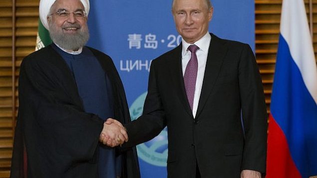 توضیح تصویر: ولادیمیر پوتین رئیس جمهور روسیه، راست، و حسن روحانی رئیس جمهور ایران حین ملاقات در کینگداو، چین، دست می‌دهند، شنبه ۹ ژوئیه ۲۰۱۸. 
(AP Photo/Alexander Zemlianichenko, Pool)