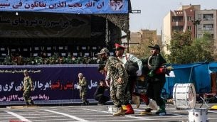 در عکسی از ۲۲ سپتامبر ۲۰۱۸ در اهواز، جنوب غرب ایران، سربازان ایرانی در حال خروج زخمی ها از صحنه پس از حمله به رژه ارتش در سالگرد آغاز جنگ ویرانگر با صدام حسین عراقی ۱۹۸۰ تا ۱۹۸۸. (AFP/ ISNA / MORTEZA JABERIAN)