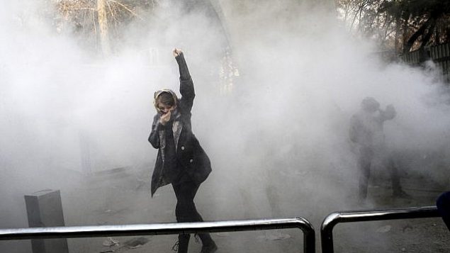 تصویر: در عکسی از ۳۰ دسامبر ۲۰۱۷، از سوی شخصی که در استخدام اسوشیتد پرس نیست، و اسوشیتد پرس عکس را در خارج از ایران ابتیاع کرده است، یک دانشجوی دانشگاه تهران، دیده می شود در حالیکه دود گلوله گاز اشک آور که پلیس ضدشورش ایران، در تهران، پرتاب کرده اطراف او را گرفته است. (AP Photo, File) تصویر: در عکسی از ۳۰ دسامبر ۲۰۱۷، از سوی شخصی که در استخدام اسوشیتد پرس نیست، و اسوشیتد پرس عکس را در خارج از ایران ابتیاع کرده است، یک دانشجوی دانشگاه تهران، دیده می شود در حالیکه دود گلوله گاز اشک آور که پلیس ضدشورش ایران، در تهران، پرتاب کرده اطراف او را گرفته است. (AP Photo, File)